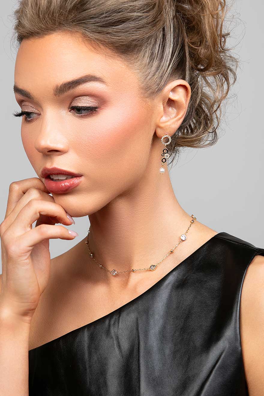 Model wearing a short gold crystal choker necklace paired with a multi-circle crystal and pearl drop earrings