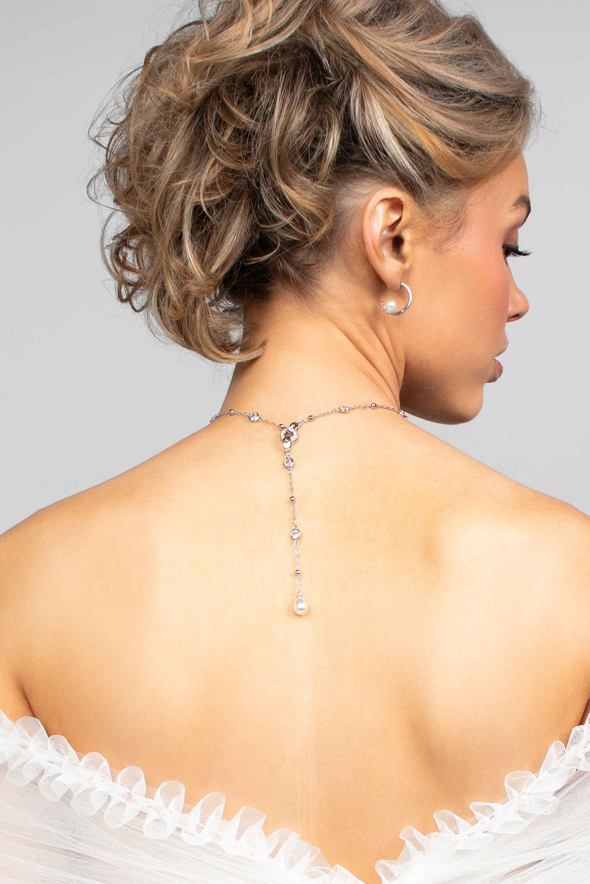 Model wearing the Palmer crystal and pearl lariat necklace in the back paired with the Prim hoop earrings