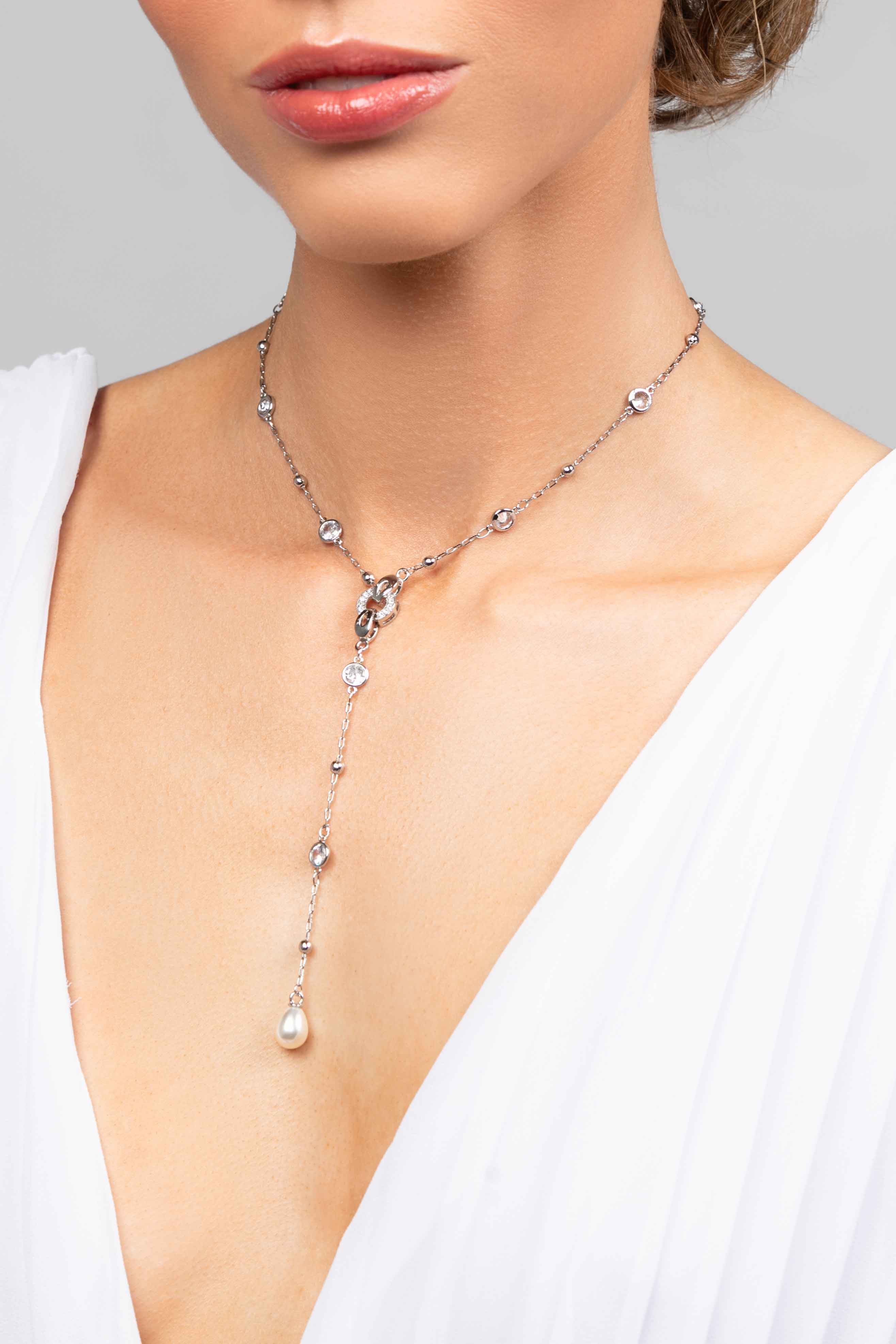 Model wearing a crystal chain lariat necklace with a pearl pendant drop