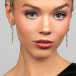 Model wearing the Ariel Taub Pearla earrings in gold which are a long drop containing 3 pearls and pave CZ crystals in between the pearls