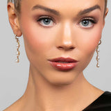 Model wearing the Ariel Taub Pearla earrings in gold which are a long drop containing 3 pearls and pave CZ crystals in between the pearls