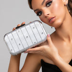 Model holding the Skye clutch in silver with Austrian crystal stripes and polka dots paired with the Sylvia earrings in silver and a sleek and modern black top.