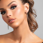 Model wearing the Sloane earrings which are a sleek long cz pave crystal spike earrings in gold.