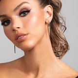 Model wearing the Sloane earrings which are a sleek long cz pave crystal spike earrings in gold.