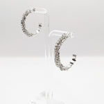 Sparkle CZ pave crystal hoop earrings show in silver on an earring stand.