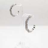 Sparkle CZ pave crystal hoop earrings show in silver on an earring stand.