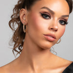 Model wearing a statement pave crystal large hoop earrings in gold
