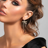 Model wearing Summer bow earrings in gold with pavé crystals and 2.25-inch drop