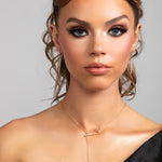 Model wearing Sutton gold lariat necklace styled in the front with matching Sloane spike earrings.