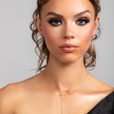 Model wearing Sutton gold lariat necklace styled in the front with matching Sloane spike earrings.