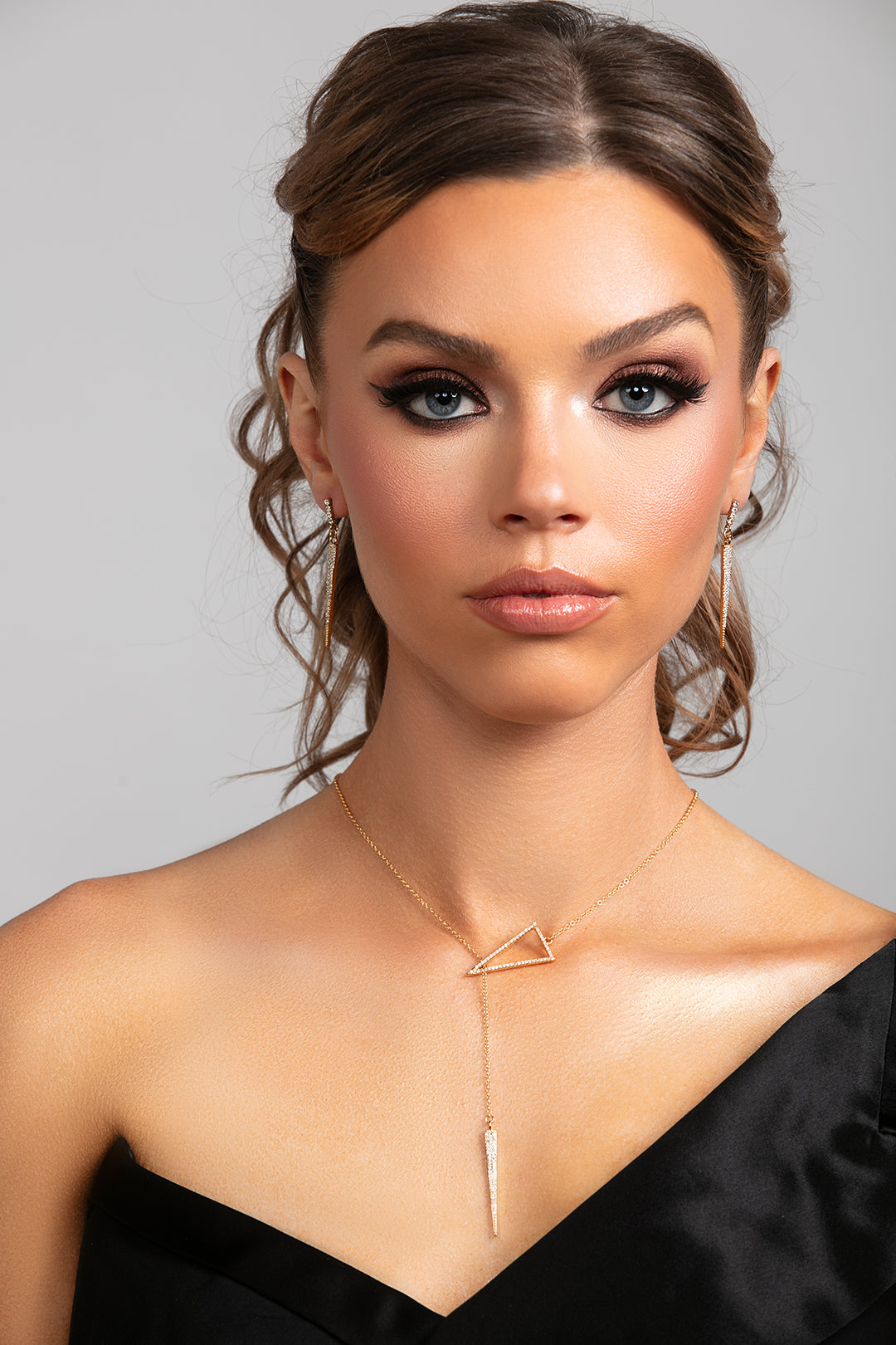 Model wearing Sutton gold lariat necklace styled in the front with matching Sloane spike earrings.