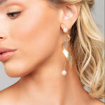 Model wearing Taylor shimmer twist pearl drop earrings in gold by Ariel Taub
