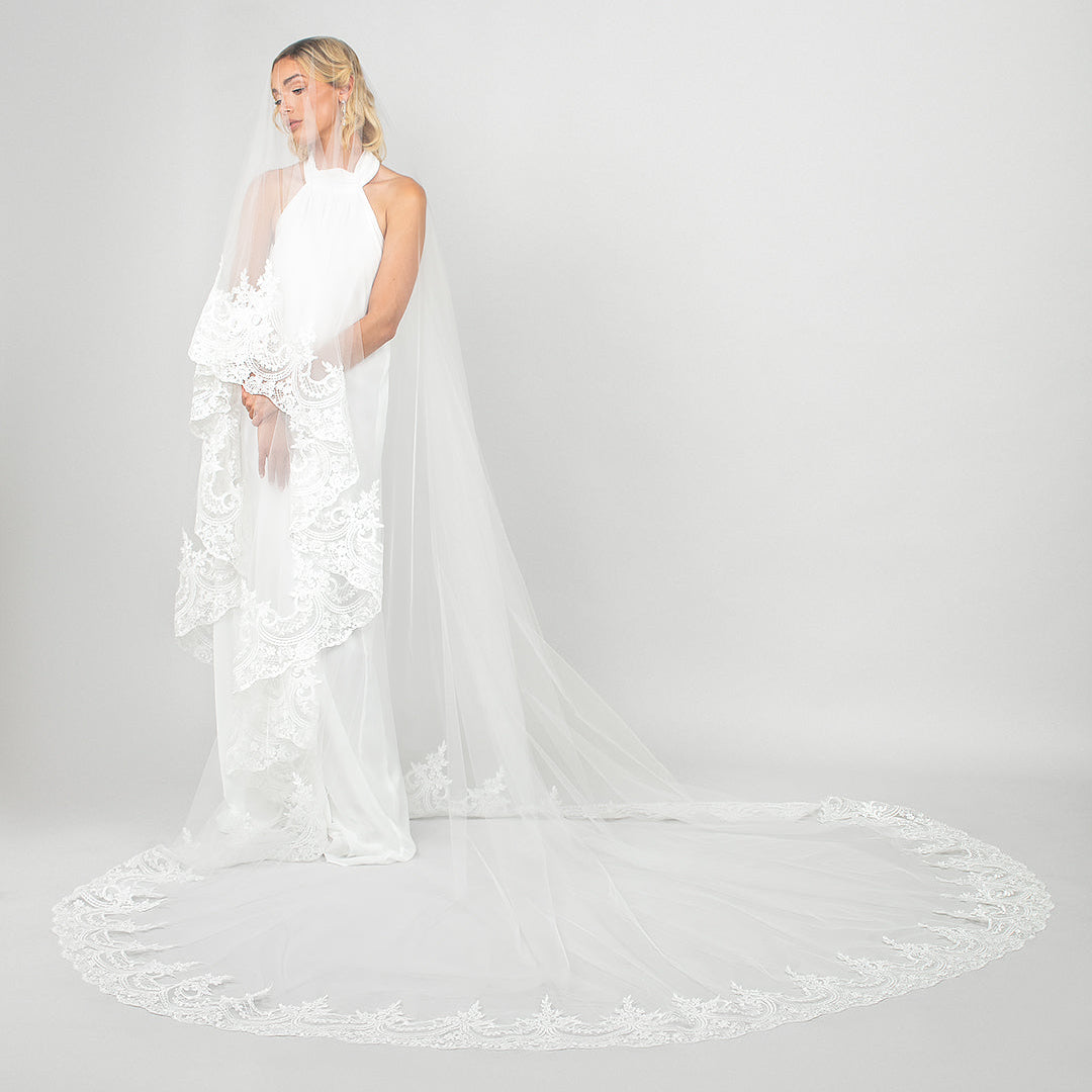 Model wearing the Ariel Taub Tiana cathedral veil with wide lace trim, and blusher pulled over