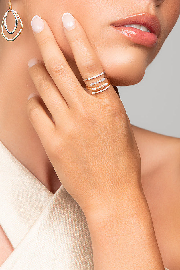 Model wearing stacked Ariel Taub Tai rings - split rings with pave crystals and pearls in gold and silver.