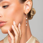 Woman wearing the Tori pearl and crystal drop earrings by Ariel Taub with a neutral background
