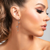 Close-up of model wearing the Sawyer earrings in silver, showing the lightweight linear drop design with polished metal spheres.