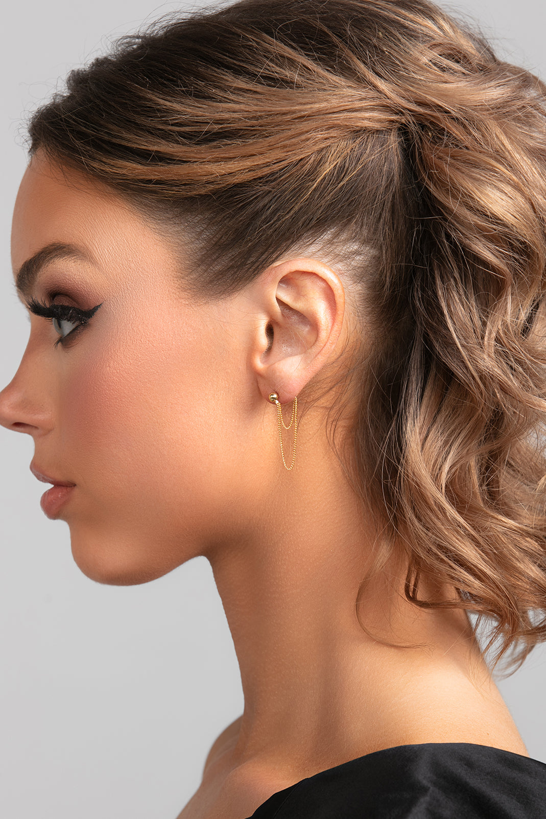 Model wearing Stevie earrings in gold with ball post and double chain drop