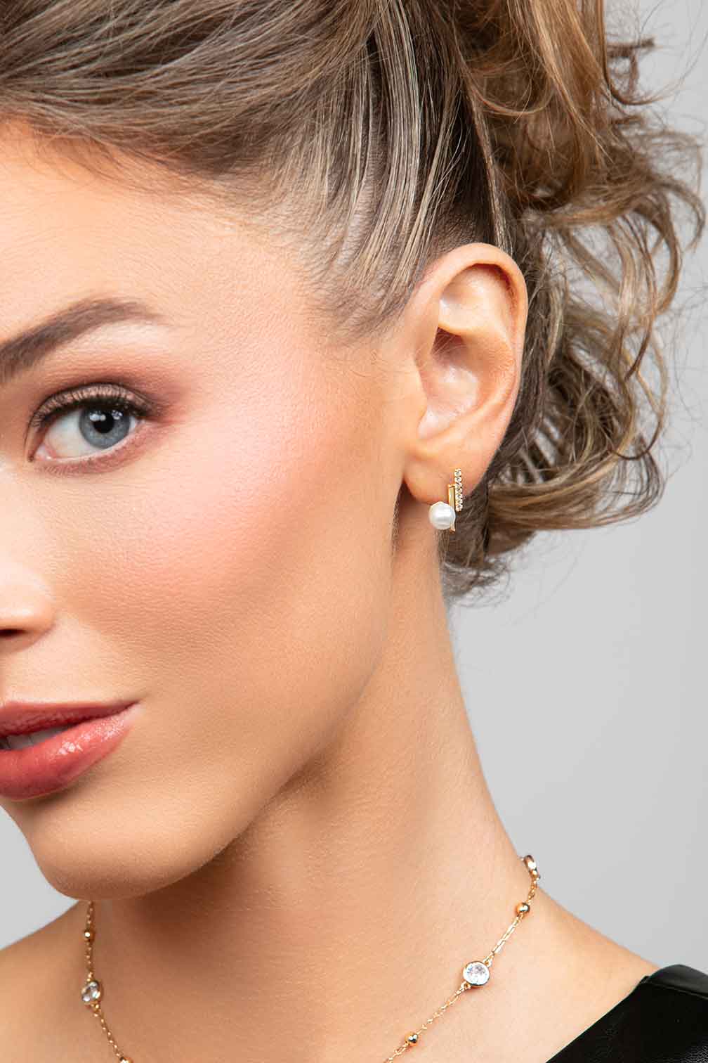 Model wearing the Ariel Taub Paxton earrings in gold which have a double bag, one with pave CZ crystals and a large pearl at the bottom