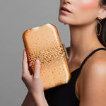 Model holding Ariel Taub’s orange crystal clutch with teal satin lining, Taylor Swift inspired accessory paired with the Lexie gold infinity earrings.