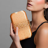 Model holding Ariel Taub’s orange crystal clutch with teal satin lining, Taylor Swift inspired accessory paired with the Lexie gold infinity earrings.