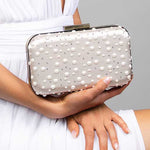 Model holding the Penelope blush satin clutch embellished with Austrian pearls and crystals in a polka dot design