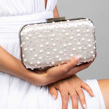 Model holding the Penelope blush satin clutch embellished with Austrian pearls and crystals in a polka dot design