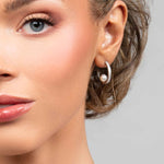 Model wearing the Prim cubic zirconia pave crystal partial hoop earrings with a floating pearl on the inside