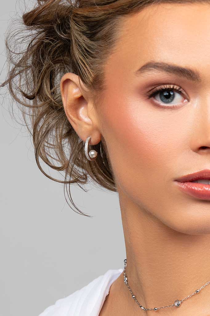 Model wearing the Prim hoop earrings which are made with CZ crystals and has a floating pearl in the back