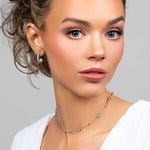 Model wearing the Prim cubic zirconia pave crystal partial hoop earrings with a floating pearl on the inside paired with a crystal choker