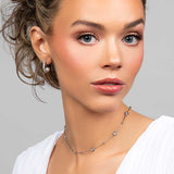 Model wearing the Prim cubic zirconia pave crystal partial hoop earrings with a floating pearl on the inside paired with a crystal choker