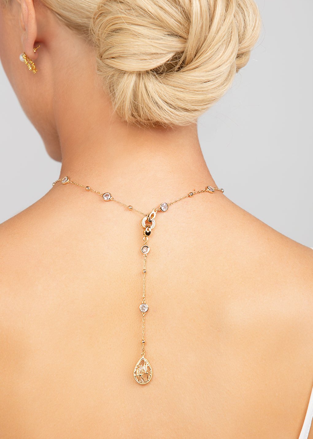 Reed detachable choker and lariat necklace shown in gold and worn in the back for elegant, modern design featuring a teardrop crystal drop in gold.