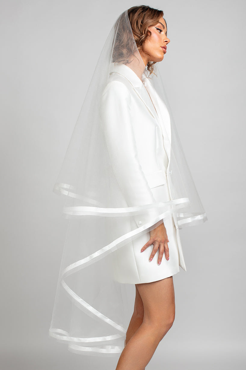 Model wearing a two-tier horsehair veil trimmed with a double face satin ribbon paired with the Andrea Osei BRIDE Renee blazer dress for a modern bridal look.