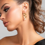 Model wearing the Serena earrings in gold which is a chain link earring with a pearl drop