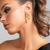Model wearing the Serena earrings in gold which is a chain link earring with a pearl drop