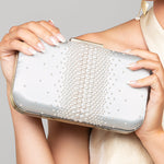 Woman holding a pearl clutch against a neutral background