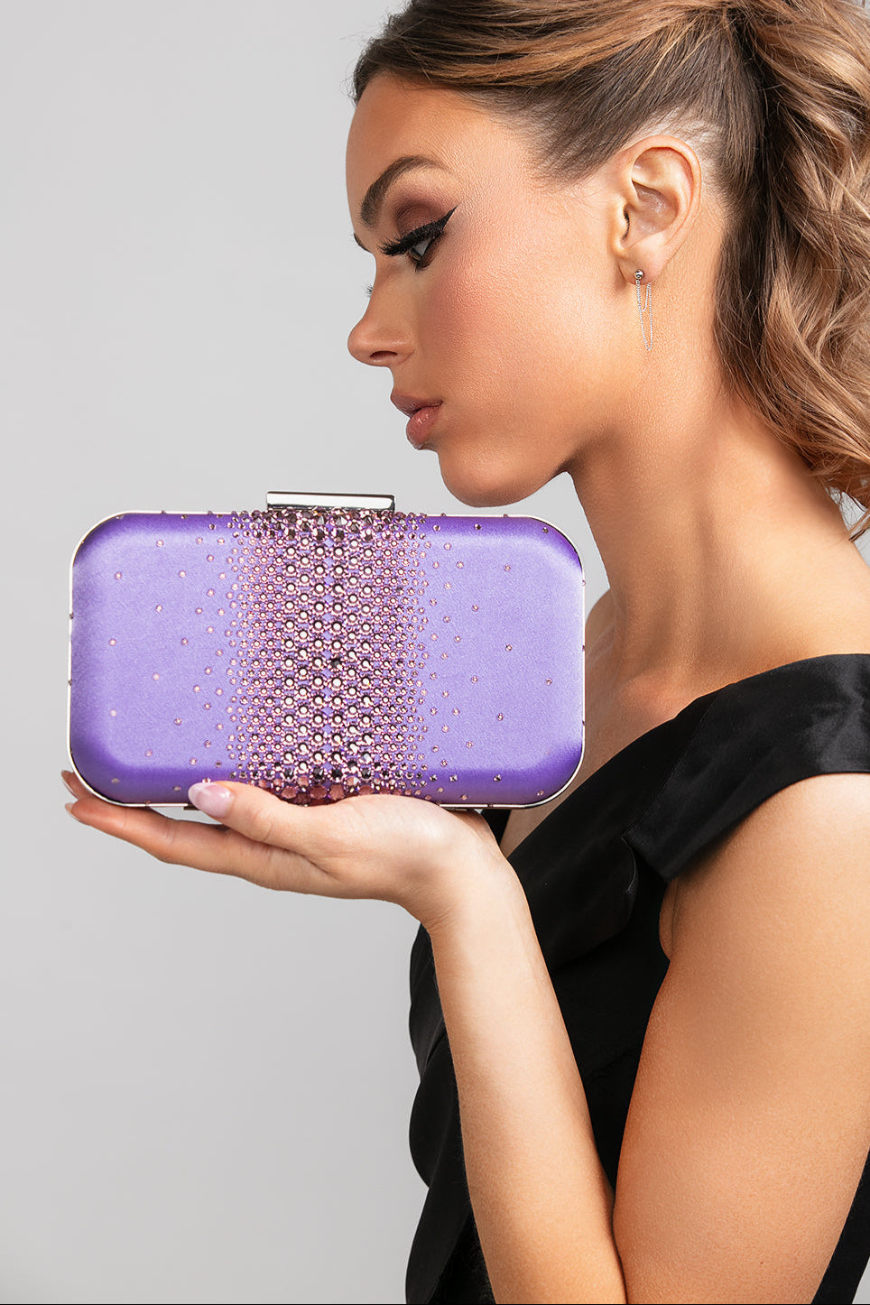 Model in a black dress holding the Ella Crystal Clutch in Lilac, showcasing the ombré crystal design and shimmering purple satin finish.