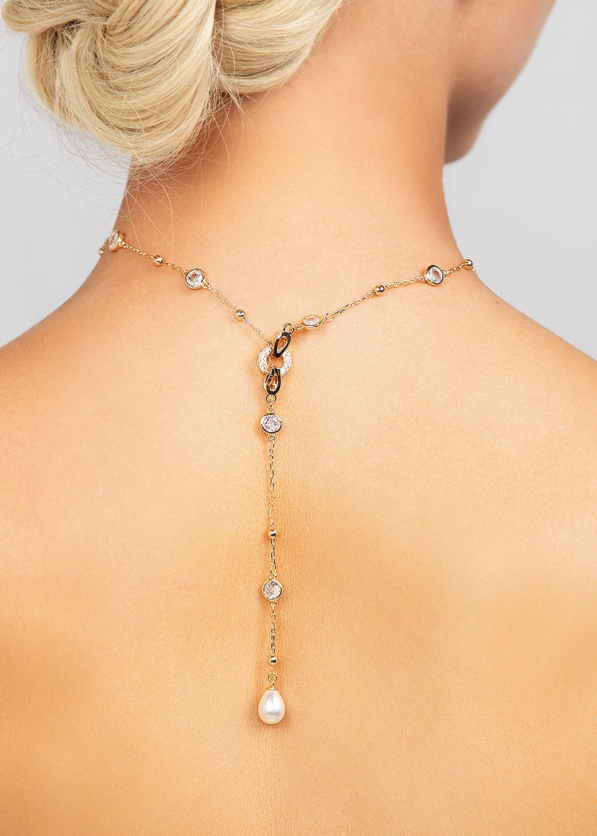 Celebrity loved gold Palmer necklace featuring a sleek and modern crystal choker chain with a detachable pearl lariat charm, shown worn in the back.