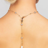 Celebrity loved gold Palmer necklace featuring a sleek and modern crystal choker chain with a detachable pearl lariat charm, shown worn in the back.