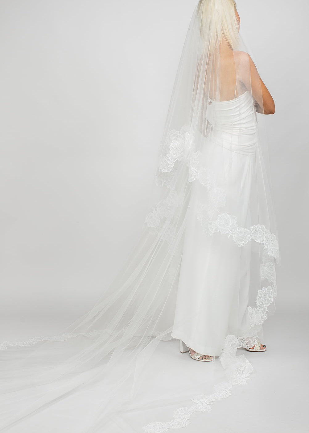 Two-tier circular cathedral-length veil with corded rose lace trimming the entire border, available in cool white and light ivory. This image shows the back view of the veil with the blusher pulled back.