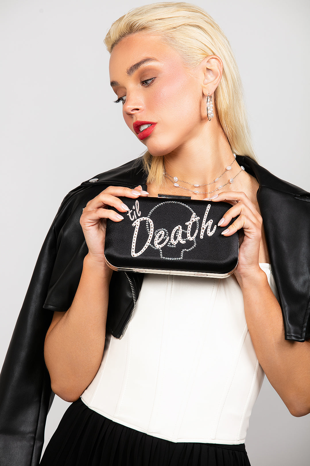 Black satin clutch with 'til death' in Austrian crystals, featuring a subtle crystal skull design for edgy brides.