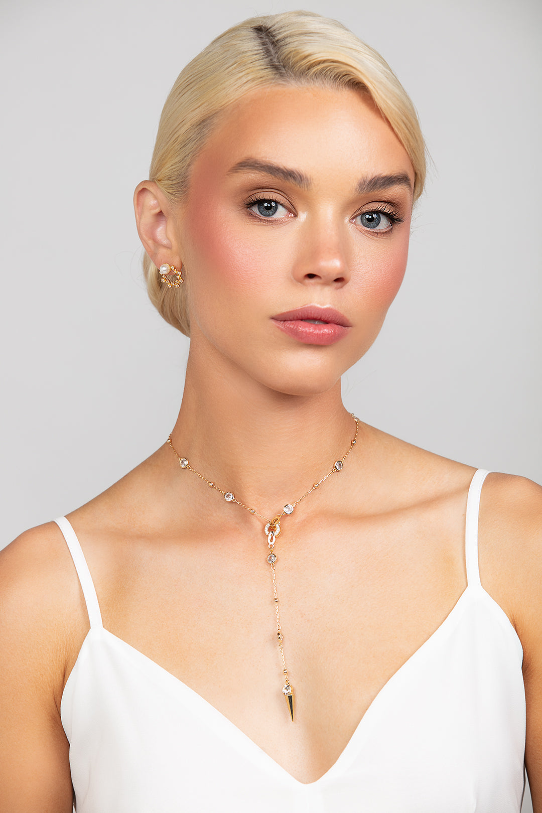 Gold Ricky necklace with a modern crystal chain and spike crystal pendant, paired with Quest sterling silver open-circle stud earrings plated in gold, featuring cubic zirconia crystals and a 6mm pearl at the top.