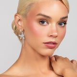 Pave crystal elongated post earrings with a crystal pave rope and pearl bow drop, designed for festive occasions. Shown in rhodium plated silver.