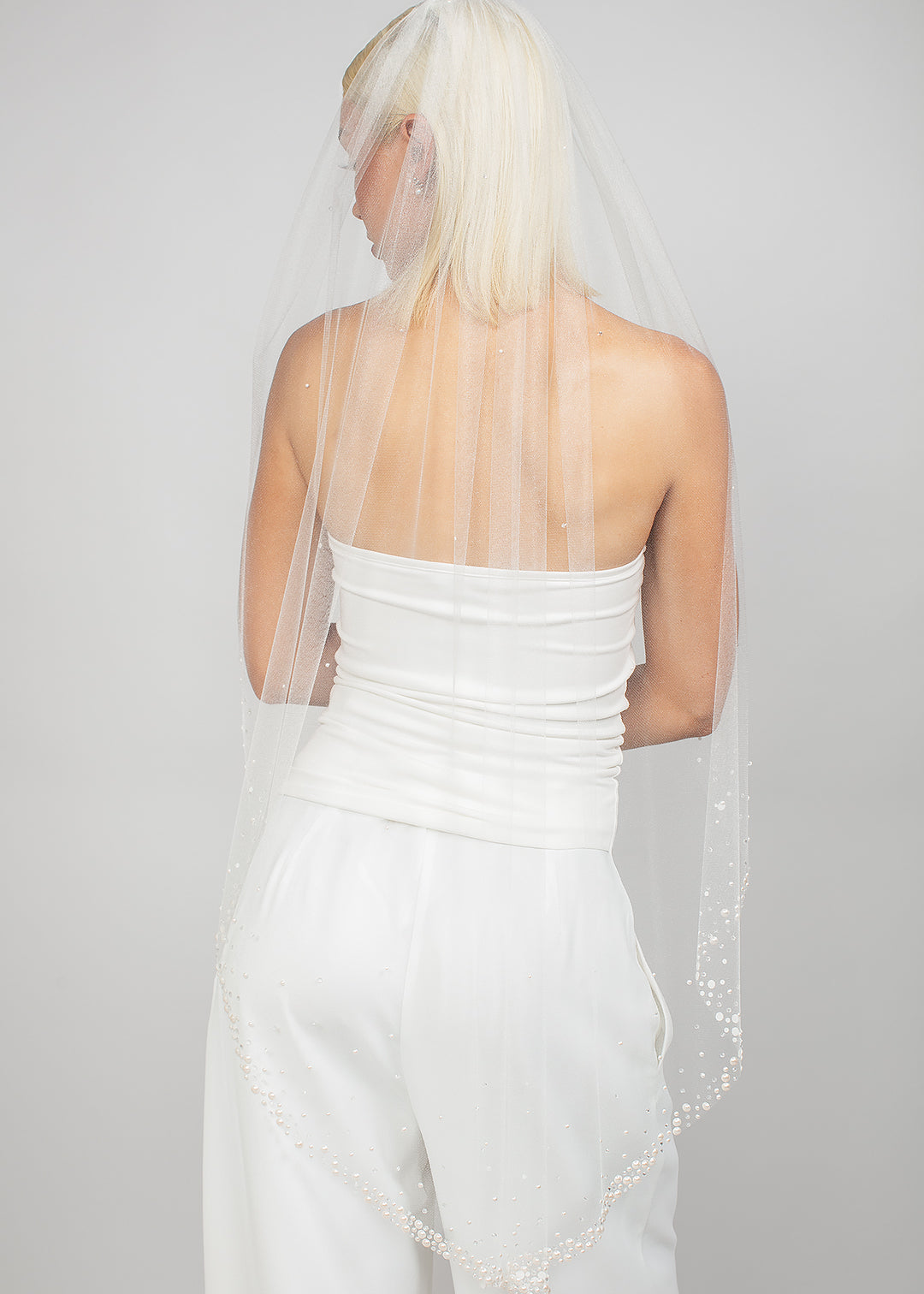 Single-tier oval-cut fingertip-length veil with clusters of Austrian pearls and see-through crystals at the bottom, fading to a light scatter.