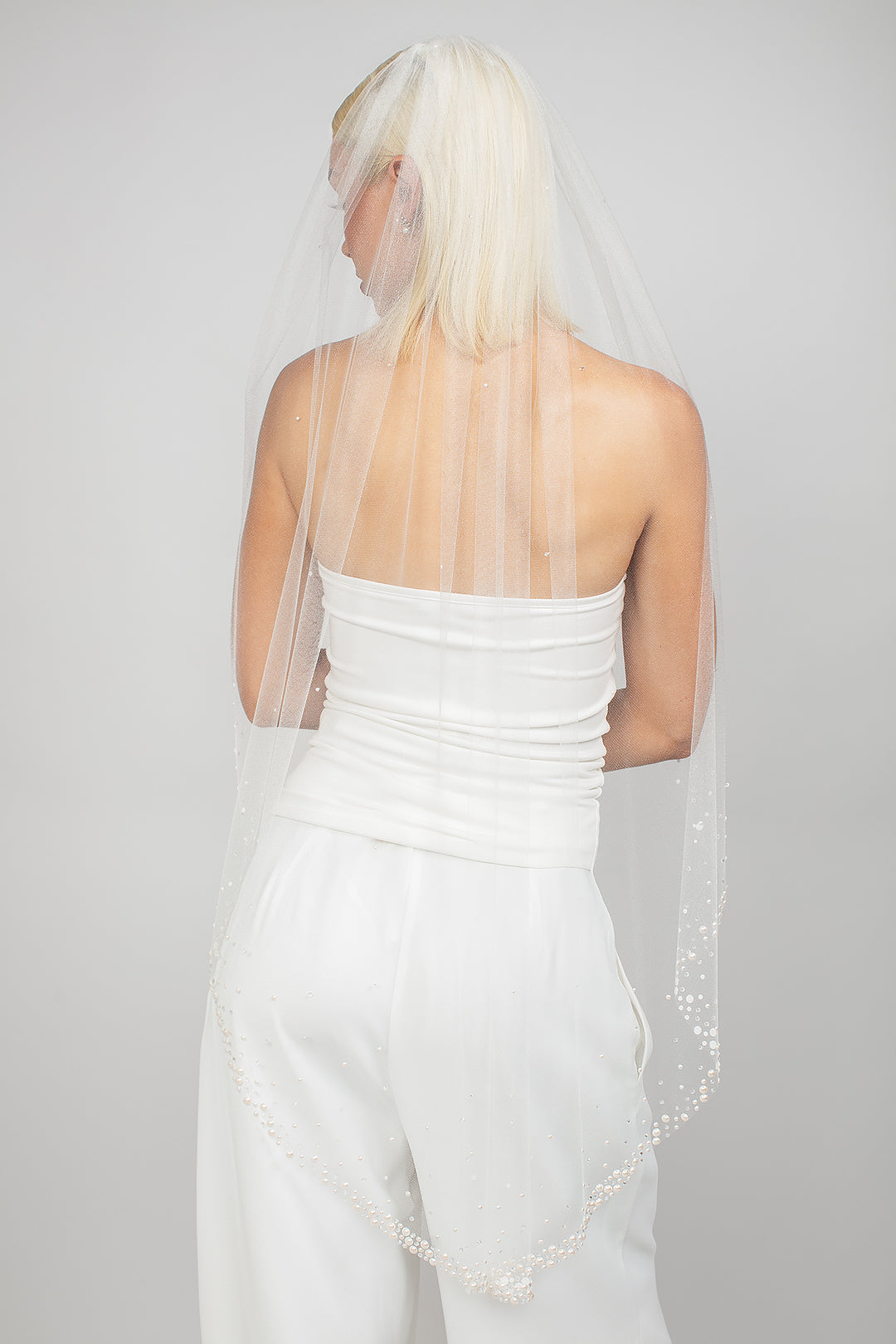 Single-tier oval-cut fingertip-length veil with clusters of Austrian pearls and see-through crystals at the bottom, fading to a light scatter.