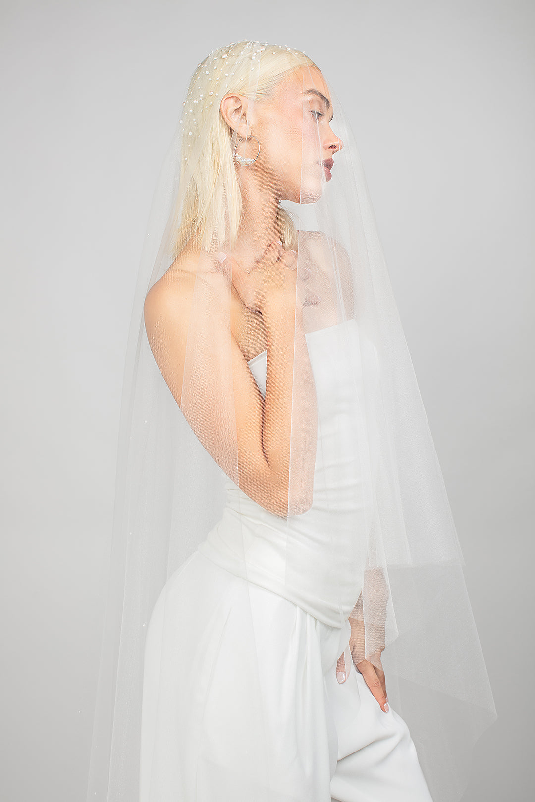 A modern cathedral wedding veil with Austrian pearls scattered throughout and dramatic cluster at the top. Shown with the blusher pulled over the face.