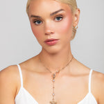 A detachable bow lariat charm necklace attached to a sparkly gold chain that can be worn as a choker as well. Front view shown in gold.