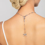 Silver Ryan bow necklace styled backwards, showcasing its pave crystal and pearl detachable bow pendant elegantly draped along the back for a unique and modern bridal or fashion statement.