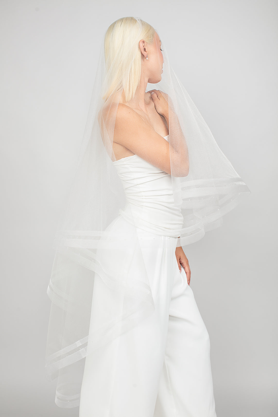 Modern two-tier double-row horsehair trimmed bridal veil with the blusher pulled over the face.