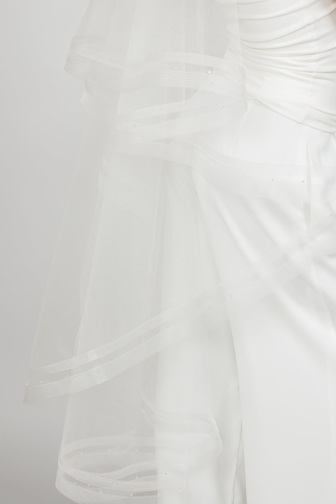 Detail shot of the two-tier waltz-length Ryder veil with a narrow double row horsehair trim and scattered Austrian see-through crystals, available in bright white and sparkly light ivory