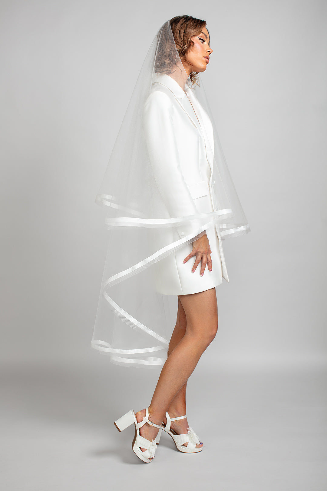 Side view of the Sadie veil highlighting its double-tiered shape, satin ribbon and horsehair trim, and elegant waltz-length silhouette.